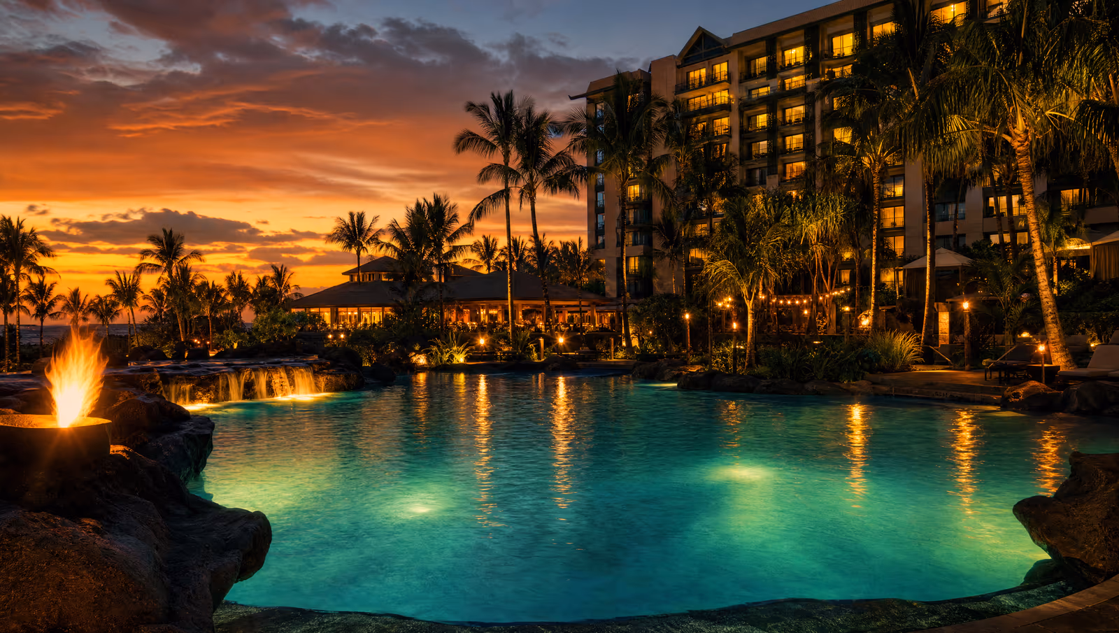 Resort pool at sunset framed by palm trees